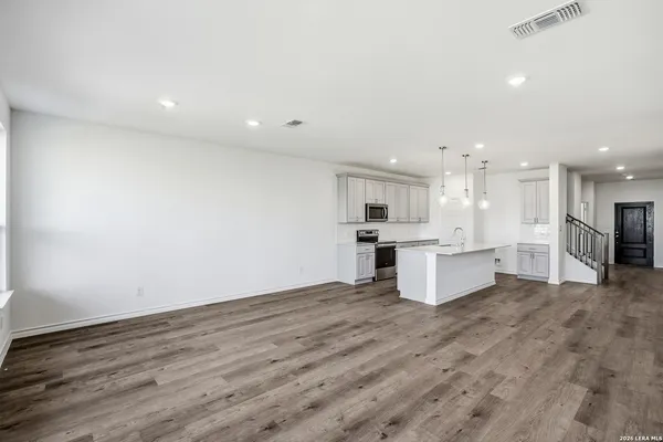 a view of kitchen with kitchen island white cabinets wooden floor and appliances