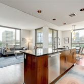 a living room with stainless steel appliances granite countertop sink stove and wooden floor