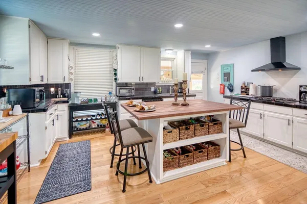 a kitchen with stainless steel appliances kitchen island granite countertop a table chairs sink and cabinets