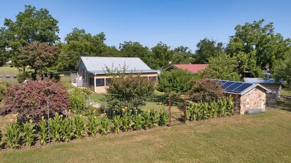 an aerial view of a house with garden space and trees all around