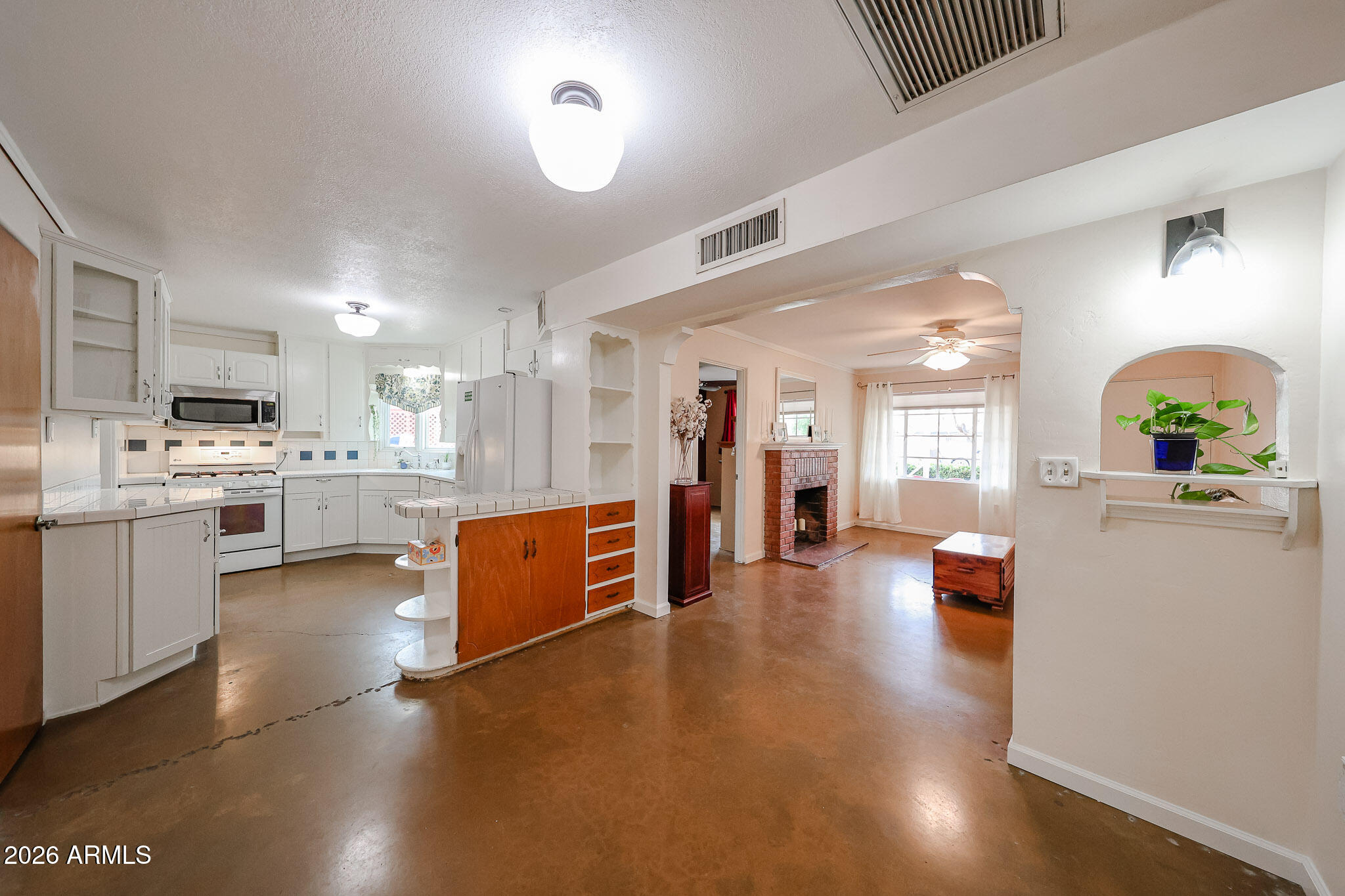 3108 North 21st Place Phoenix, AZ 85016 - Photo 13 of 56 a kitchen with stainless steel appliances a stove a sink a refrigerator white cabinets and couches with wooden floor
