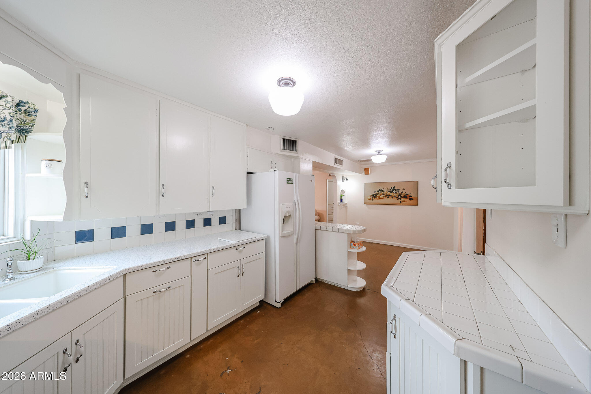 3108 North 21st Place Phoenix, AZ 85016 - Photo 18 of 56 a large white kitchen with a refrigerator a sink dishwasher and white cabinets with wooden floor