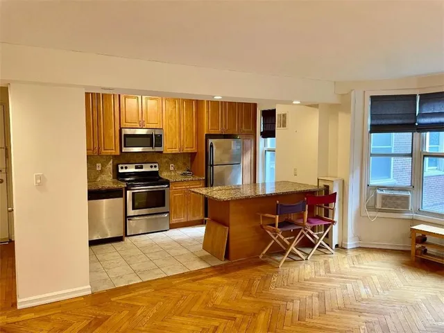a kitchen with stainless steel appliances kitchen island granite countertop a refrigerator and a stove top oven