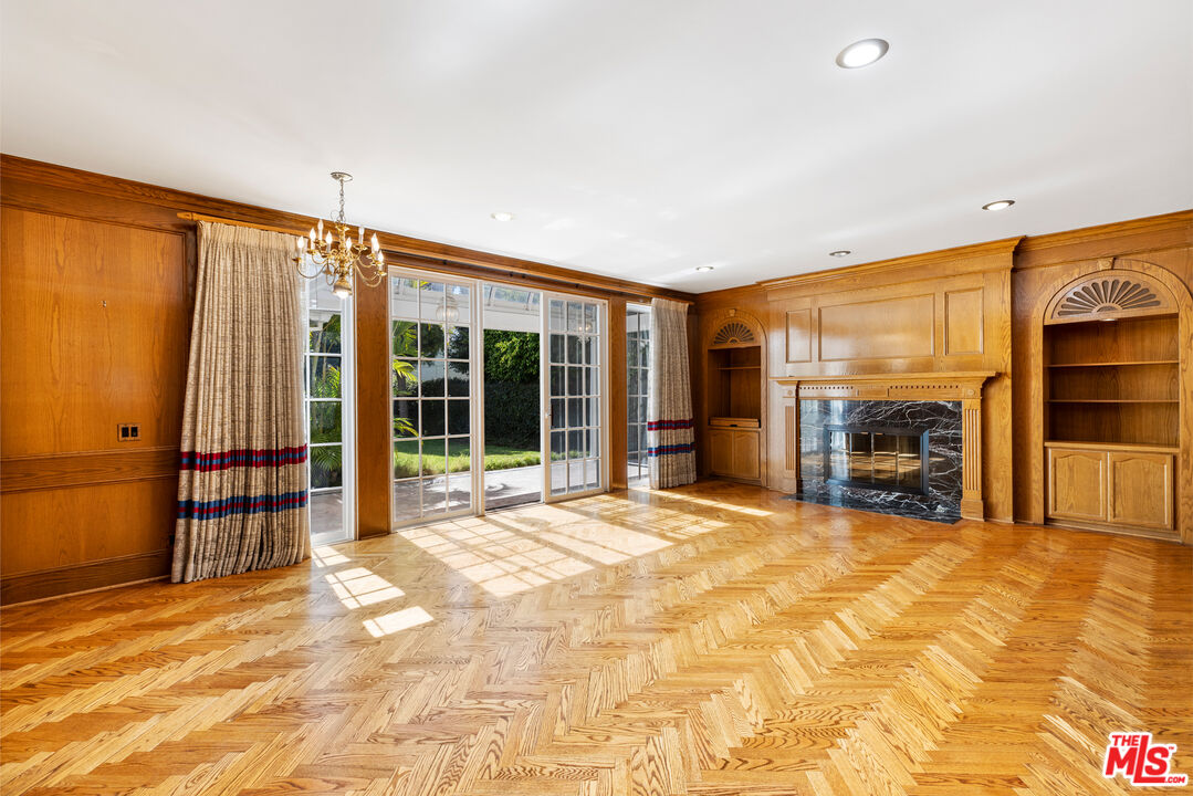 218 Foothill Road Beverly Hills, CA 90210 - Photo 4 of 16 a view of an empty room with a fireplace and a large window