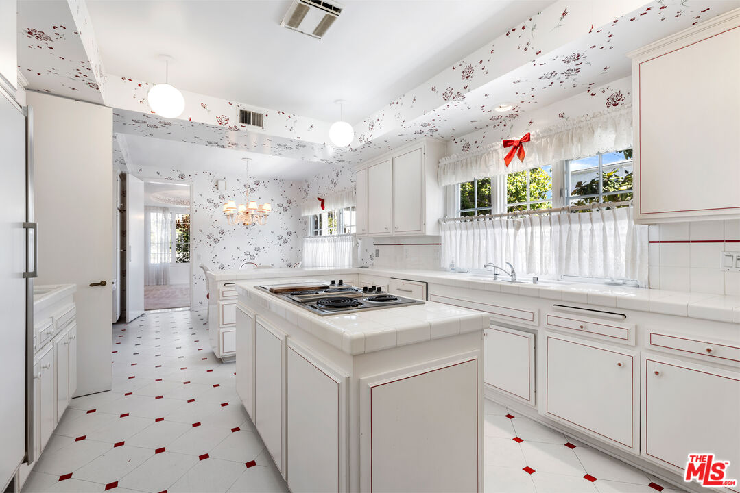 218 Foothill Road Beverly Hills, CA 90210 - Photo 7 of 16 a kitchen with white cabinets a sink stove and refrigerator