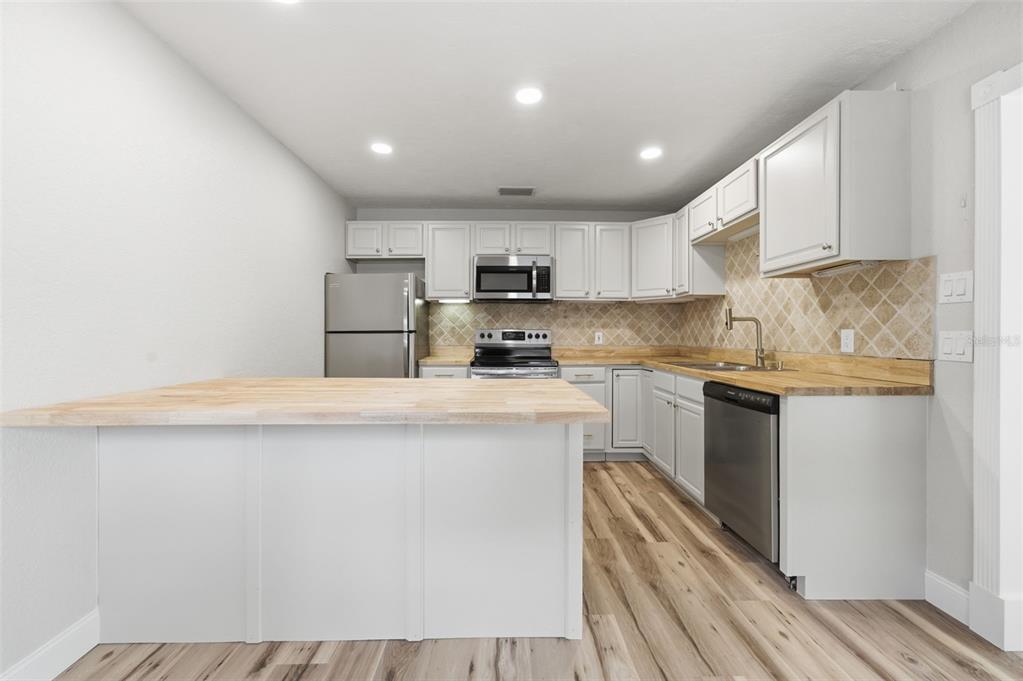 5340 Dartmouth Road New Port Richey, FL 34652 - Photo 16 of 41 a kitchen with a refrigerator a stove top oven and white cabinets with wooden floor