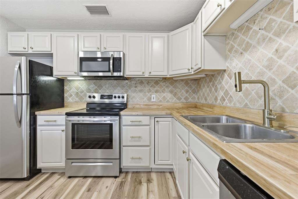 5340 Dartmouth Road New Port Richey, FL 34652 - Photo 5 of 41 a kitchen with granite countertop white cabinets stainless steel appliances and a sink