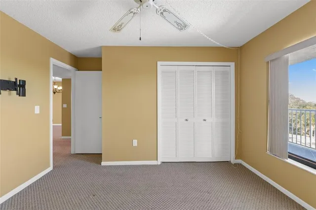 an empty room with windows and chandelier fan
