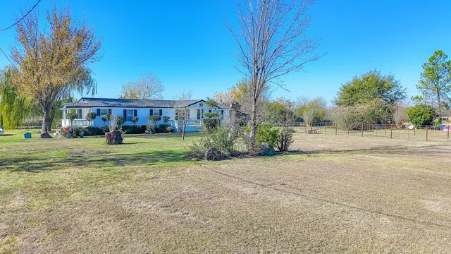 a view of an house with backyard and trees