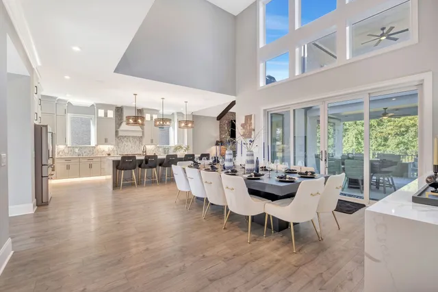 a view of a dining room and livingroom with furniture wooden floor a rug and a chandelier