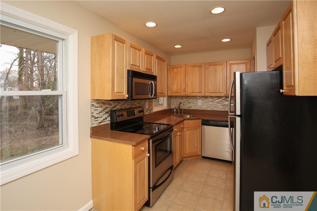 10 Gurley Road Edison, NJ 08817 - Photo 6 of 17 a kitchen with a refrigerator a stove top oven a sink and a window