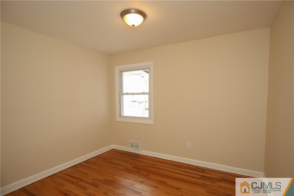 10 Gurley Road Edison, NJ 08817 - Photo 8 of 17 an empty room with wooden floor and windows