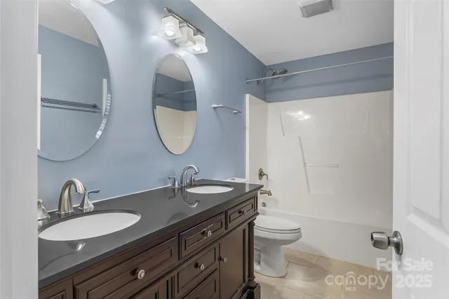 a bathroom with a double vanity sink double mirror and toilet