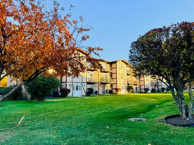 a view of a building with a big yard and large trees