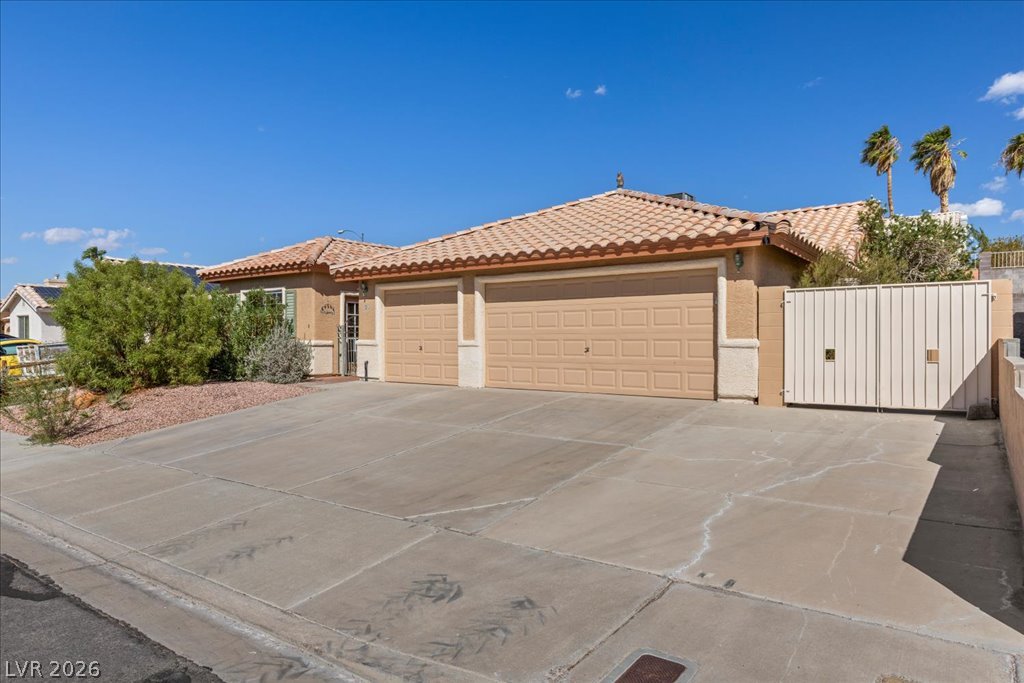 120 Ringlore Road Henderson, NV 89015 - Photo 4 of 58 An expansive concrete driveway leads to a classic stucco exterior with Spanish tile roofing.