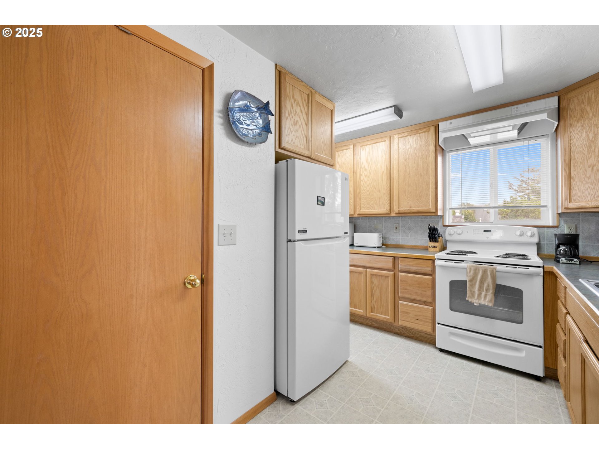 337 16th Avenue Seaside, OR 97138 - Photo 11 of 38 a kitchen with a refrigerator and white cabinets
