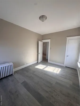 a view of an empty room and window and wooden floor