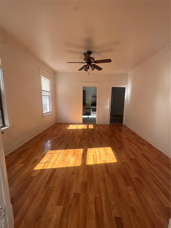 a view of a livingroom with wooden floor a ceiling fan and a fireplace