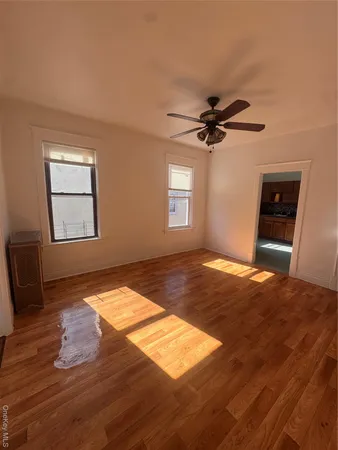 a view of empty room with wooden floor and fan