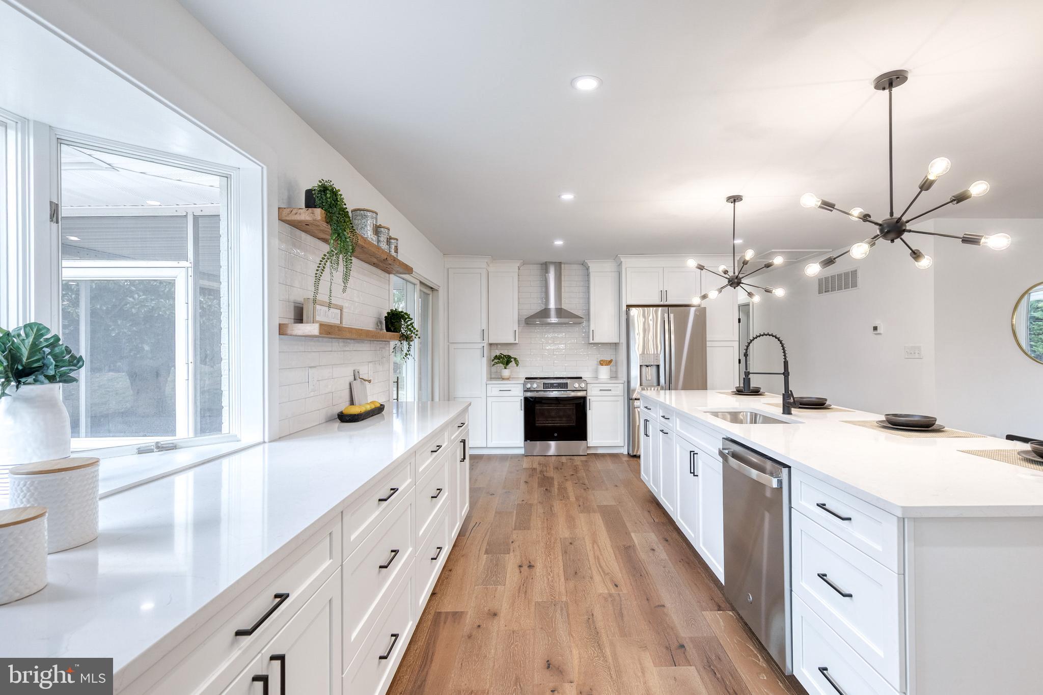 4011 Perry Hall Road Perry Hall, MD 21128 - Photo 29 of 51 a large kitchen with kitchen island a stove a sink a refrigerator and a dining table with wooden floor