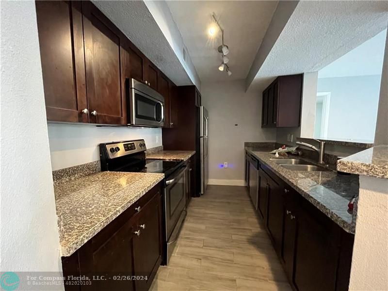 a kitchen with granite countertop stainless steel appliances a sink stove top oven and cabinets