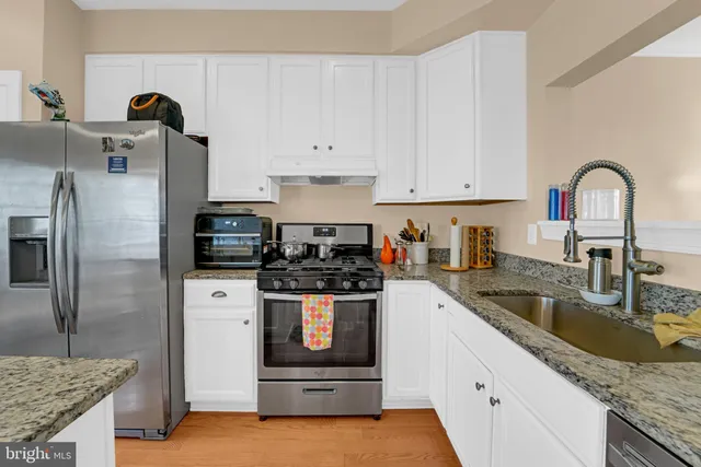 a kitchen with stainless steel appliances kitchen island granite countertop a stove and white cabinets