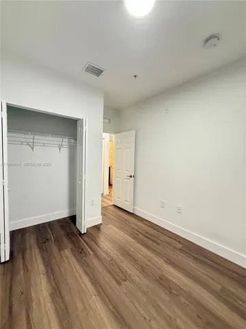 an empty room with wooden floor & windows