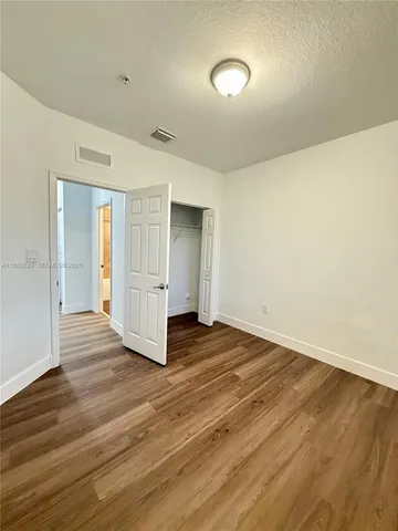 a view of an empty room with wooden floor and closet