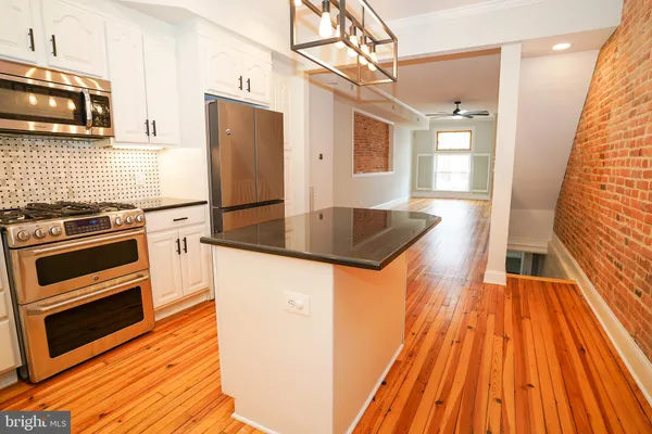 a kitchen with granite countertop wooden floors and stainless steel appliances