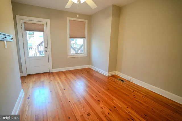 an empty room with wooden floor and windows