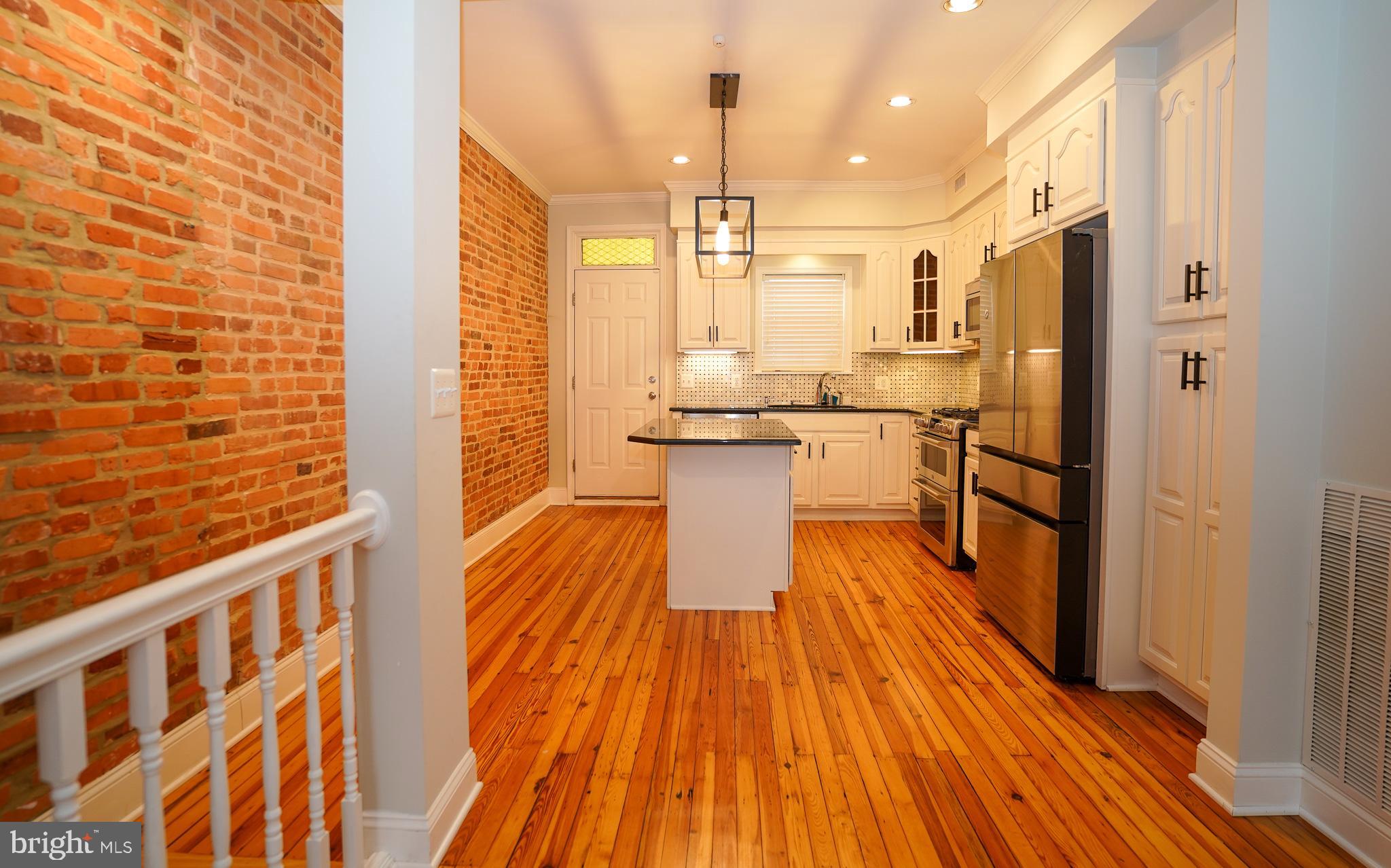 713 South Linwood Avenue Baltimore, MD 21224 - Photo 8 of 32 a kitchen with stainless steel appliances a refrigerator and wooden floor
