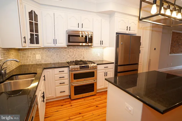 a kitchen with granite countertop a refrigerator sink and stove