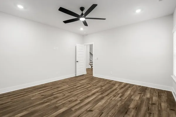 an empty room with wooden floor and ceiling fan