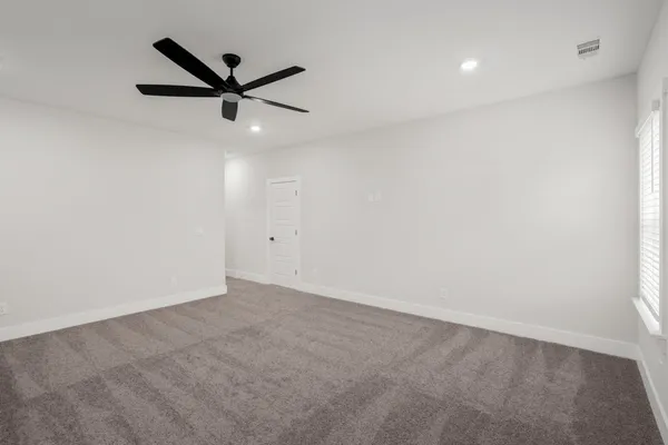 an empty room with a ceiling fan and a window