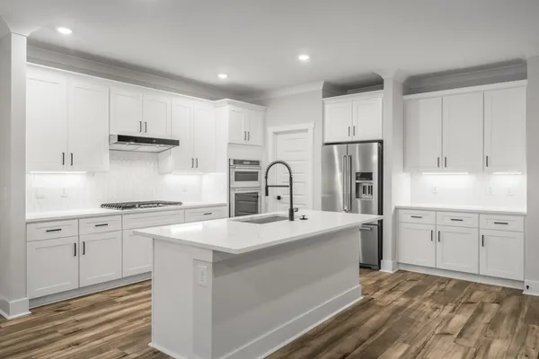 a kitchen with white cabinets a sink stove and refrigerator