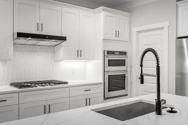 a kitchen with stainless steel appliances kitchen island a stove and white cabinets