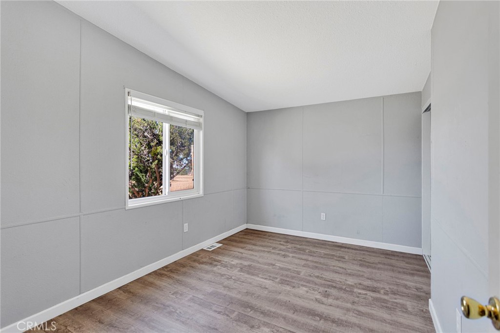 8074 Mira Mar Road Phelan, CA 92371 - Photo 22 of 49 a view of an empty room with wooden floor and a window