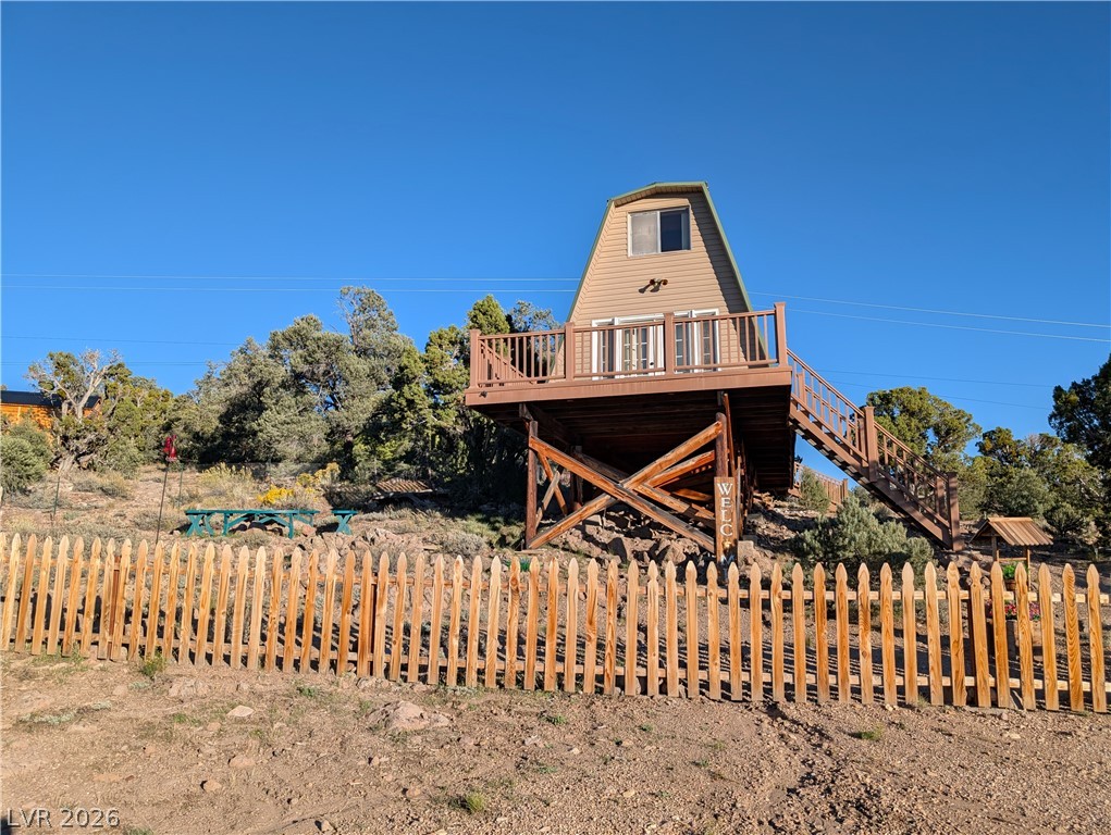 20502 Windsong Road Pioche, NV 89043 - Photo 2 of 30 An elevated wood cabin sits perched on a hillside behind a classic picket fence.