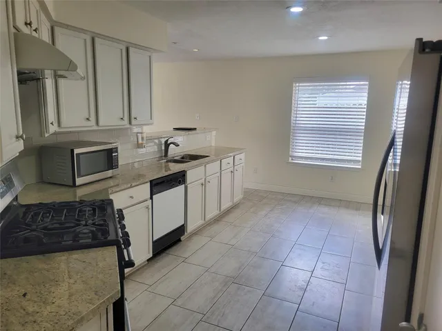 a kitchen with stainless steel appliances granite countertop a sink stove and cabinets