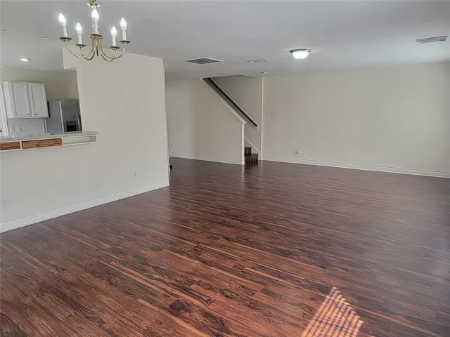 a view of an empty room with wooden floor and a fireplace