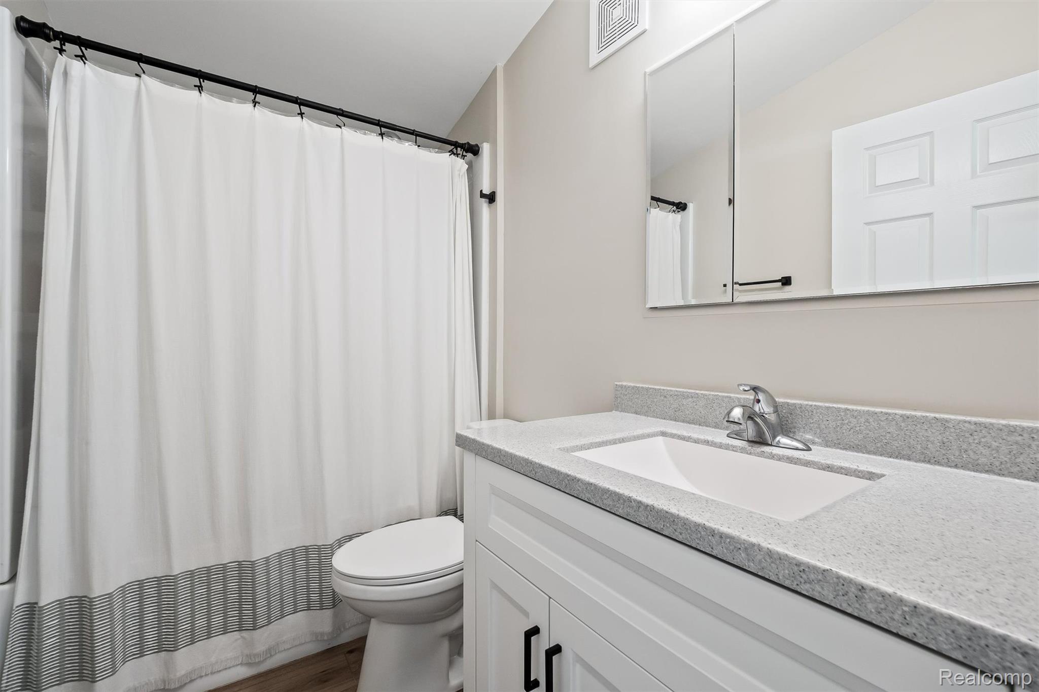 870 Pine Tree Road Lake Orion, MI 48362 - Photo 16 of 32 Bathroom featuring a white vanity with paneling, a light-toned countertop, and an integrated rectangular sink