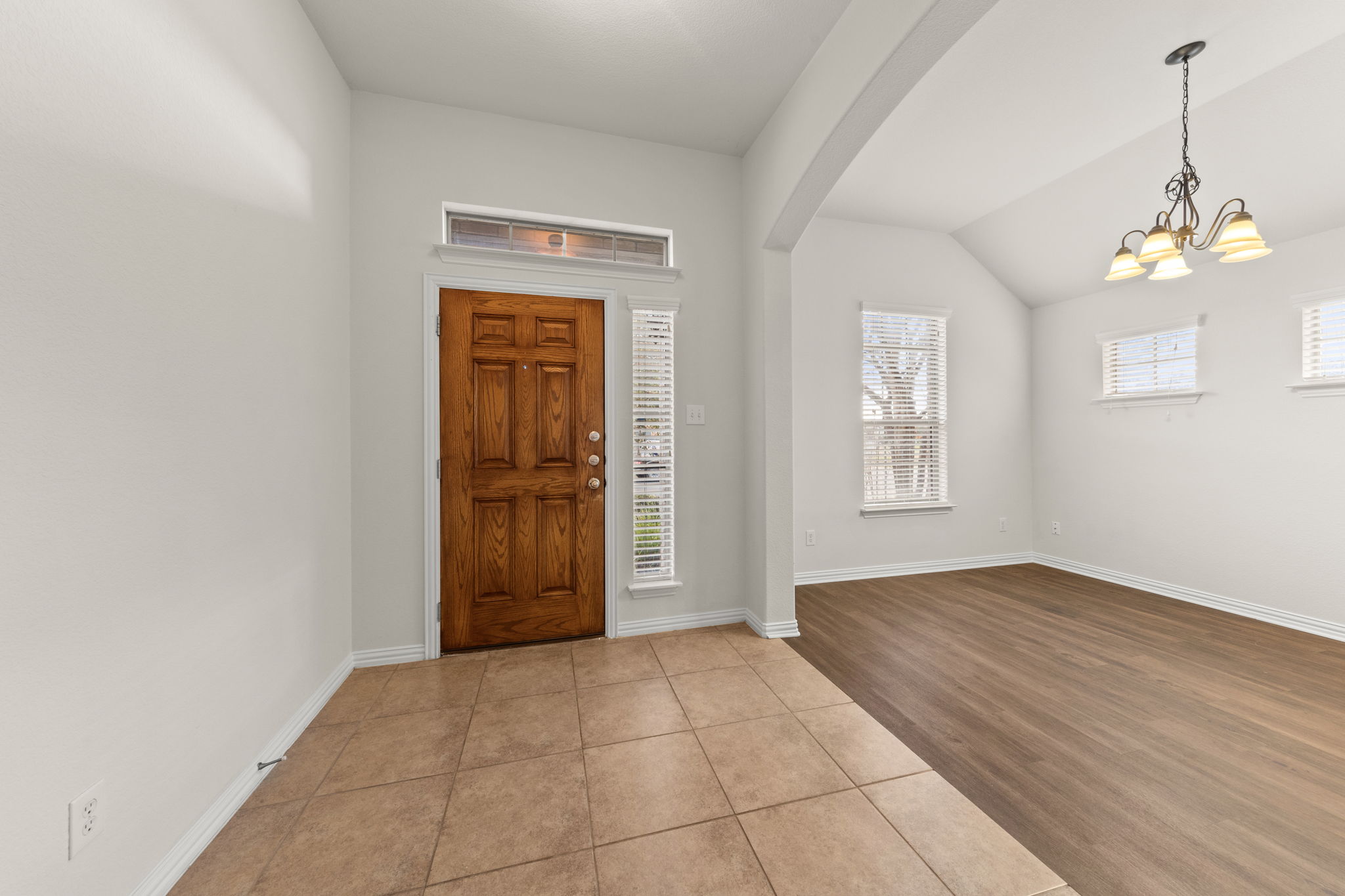 411 Tascate Street Georgetown, TX 78628 - Photo 4 of 41 A welcoming entry features tile flooring, leading into an open living space with warm wood floors and vaulted ceilings.