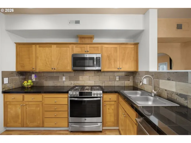 a kitchen with stainless steel appliances granite countertop a sink stove and microwave