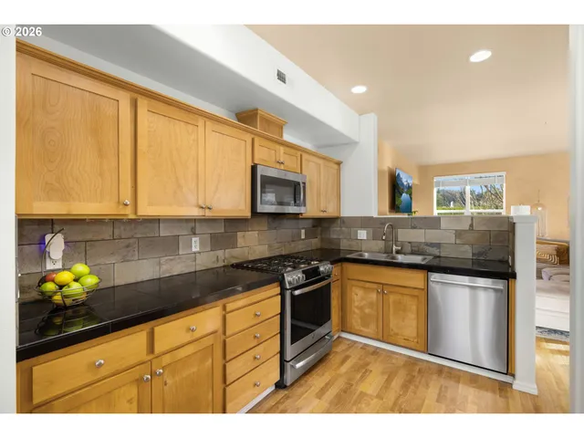 a kitchen with stainless steel appliances granite countertop a stove a sink and a microwave