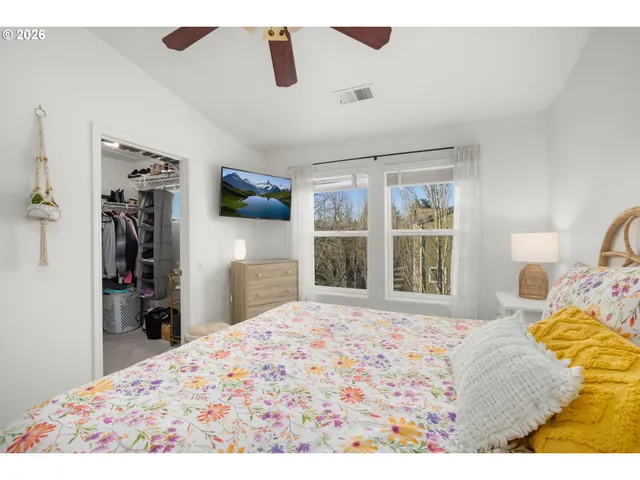 a bedroom with a bed and a flat tv screen on dresser