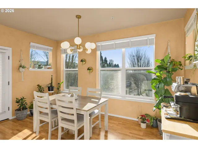 a dining room with wooden floor a chandelier a glass table and chairs