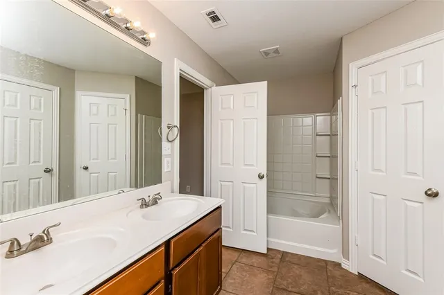 a bathroom with a tub sink vanity granite and shower
