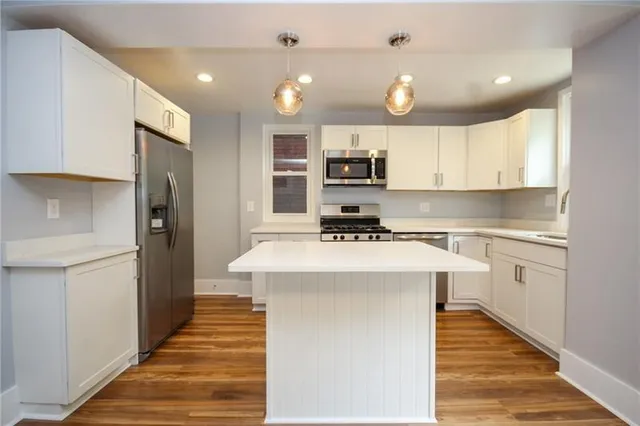a kitchen with kitchen island stainless steel appliances a sink and cabinets