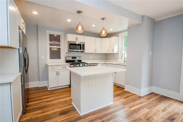 a kitchen with kitchen island granite countertop a sink cabinets and stainless steel appliances