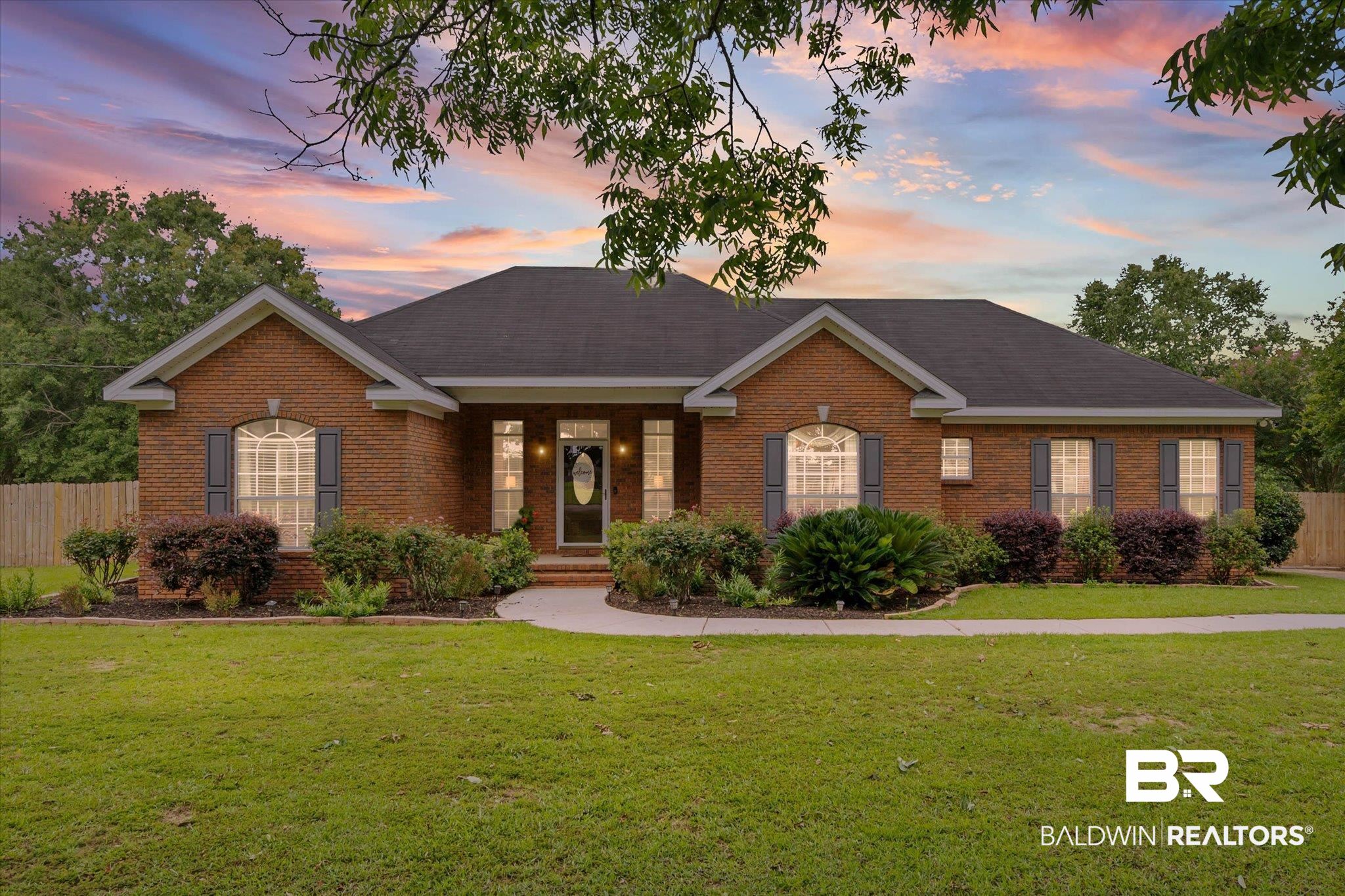 3170 Scott Dairy Loop Road West Mobile, AL 36695 - Photo 1 of 24 Brick exterior featuring a dark asphalt shingle roof, a curving concrete walkway, mature landscaping, and a fenced perimeter